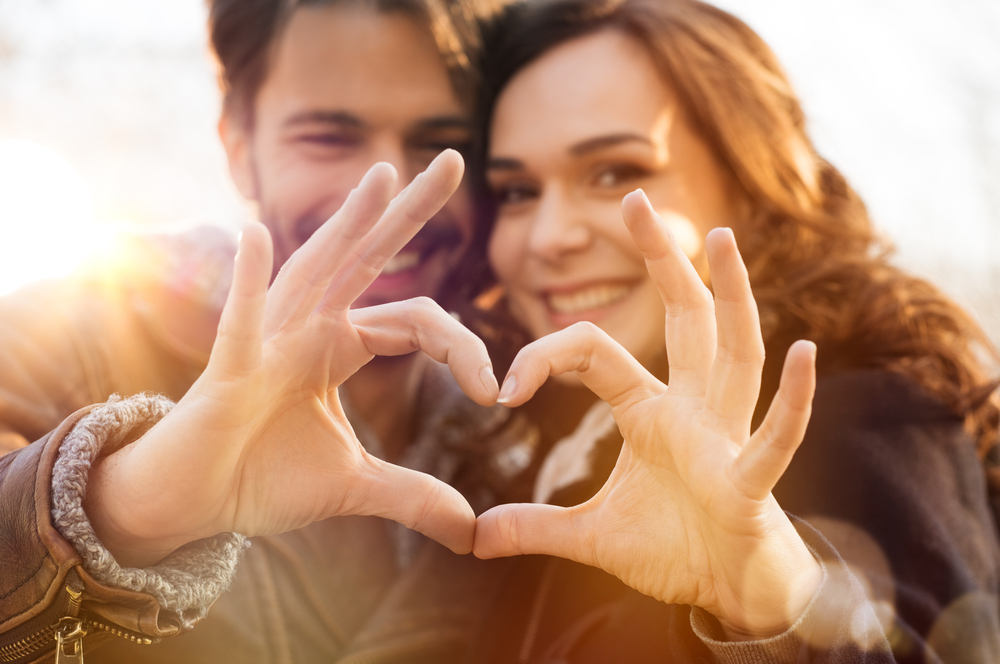 Closeup of couple making heart shape with hands after reading a romantic bedtime story