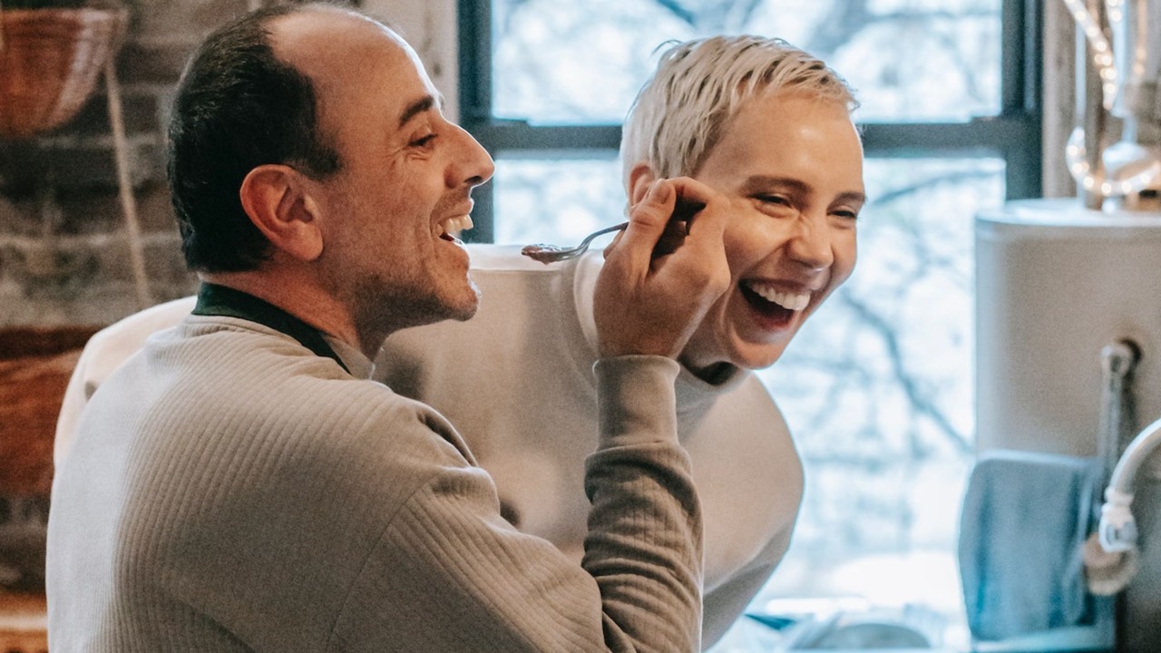 Laughing couple preparing food in kitchen